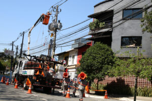 Funcionários da Enel fazem manutenção em poste de energia elétrica no bairro de Pinheiros.