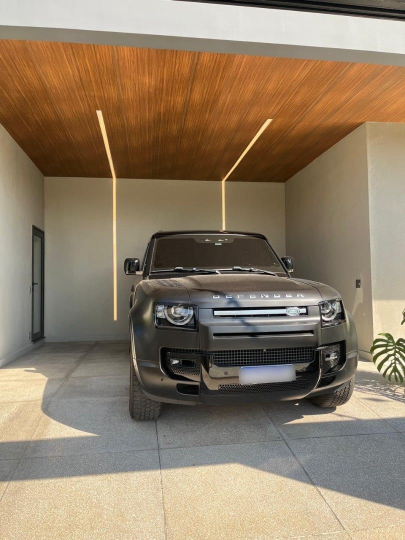 Carro de luxo preto, modelo Defender, estacionado em garagem de casa de alto padrão