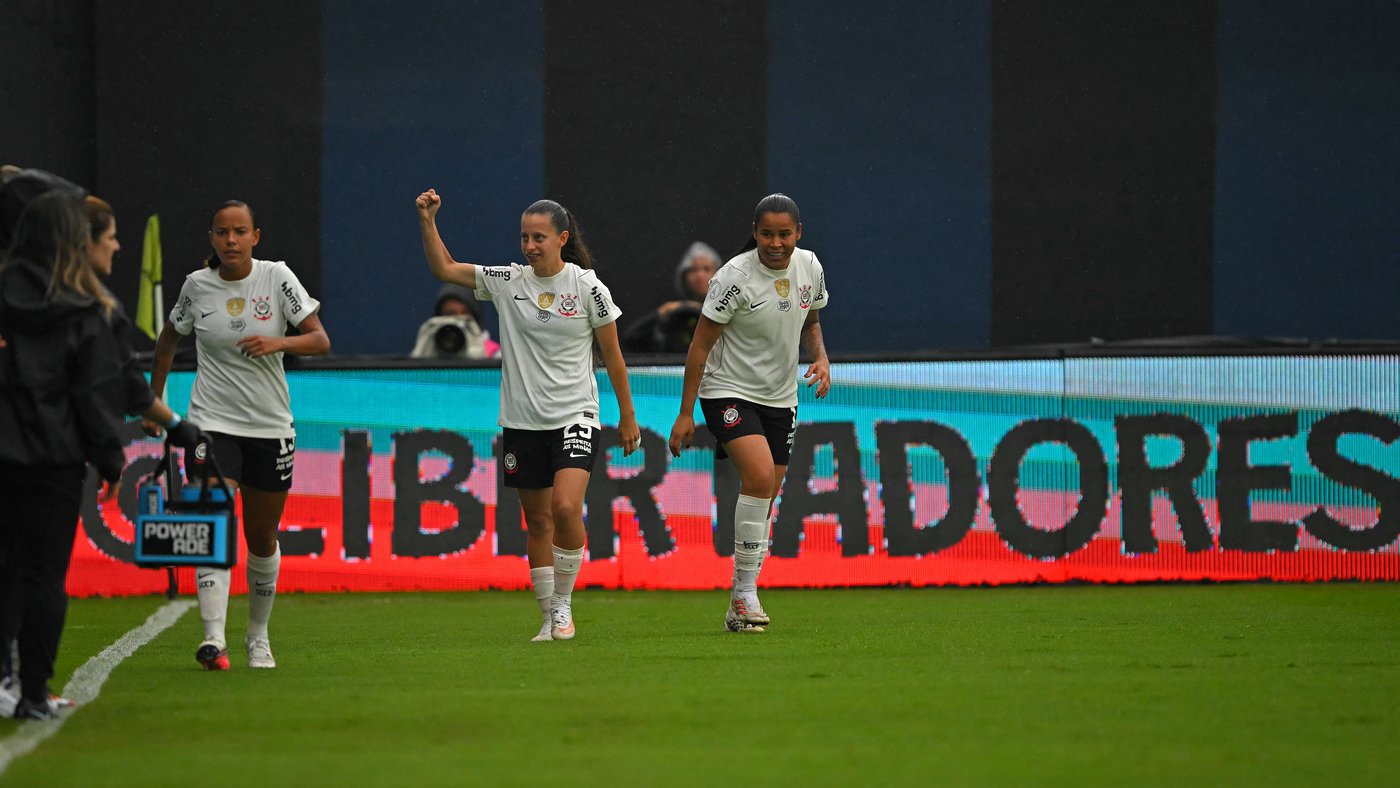 Jogadoras do Corinthians caminham no gramado ao lado da placa da Libertadores, em Quito