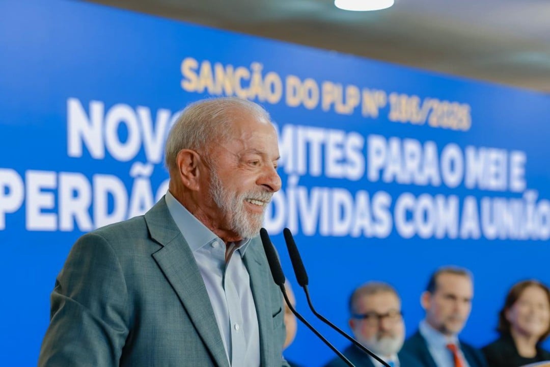 Lula discursa em cerimônia com painel azul ao fundo que anuncia a sanção do PLP 186/2026 e o perdão de dívidas com a União