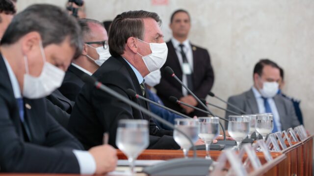 Jair Bolsonaro de máscara branca em coletiva sobre o coronavírus, ao lado de ministros, em março de 2020