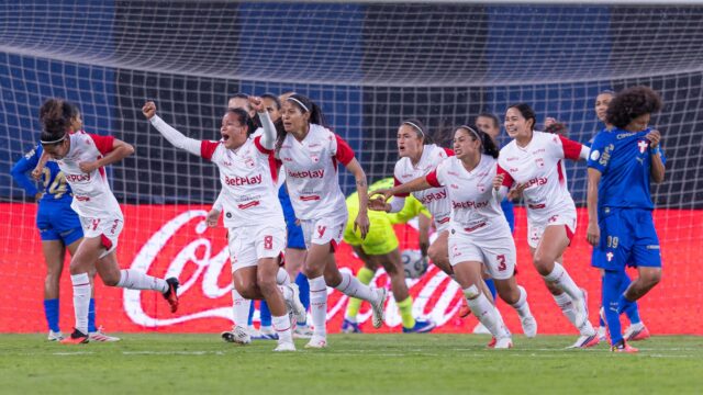 Jogadoras do Santa Fe comemoram de braços erguidos após a classificação nos pênaltis, com jogadoras do Palmeiras de cabeça baixa ao fundo