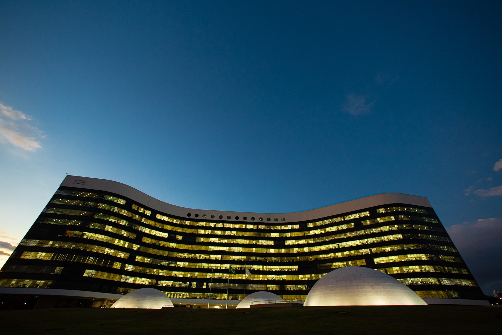 Fachada iluminada do prédio do Tribunal Superior Eleitoral, em Brasília, ao anoitecer