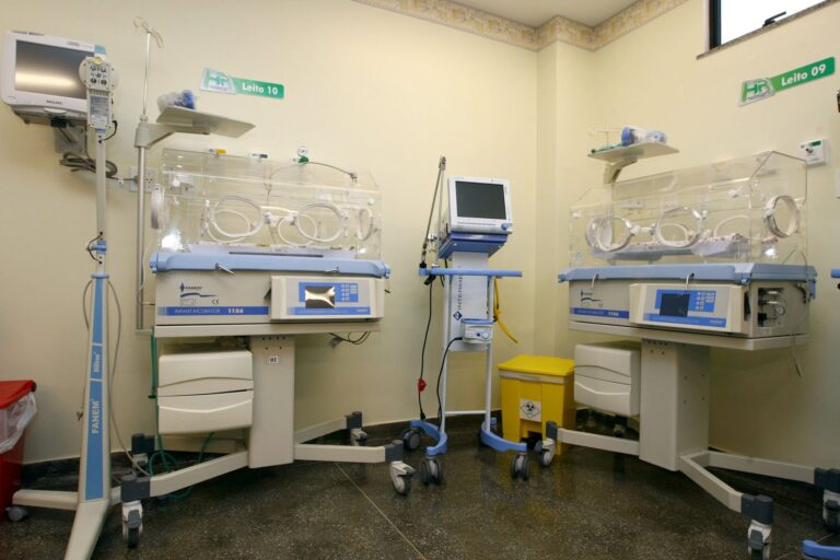 Sala de UTI neonatal com incubadoras, monitores e berços numerados