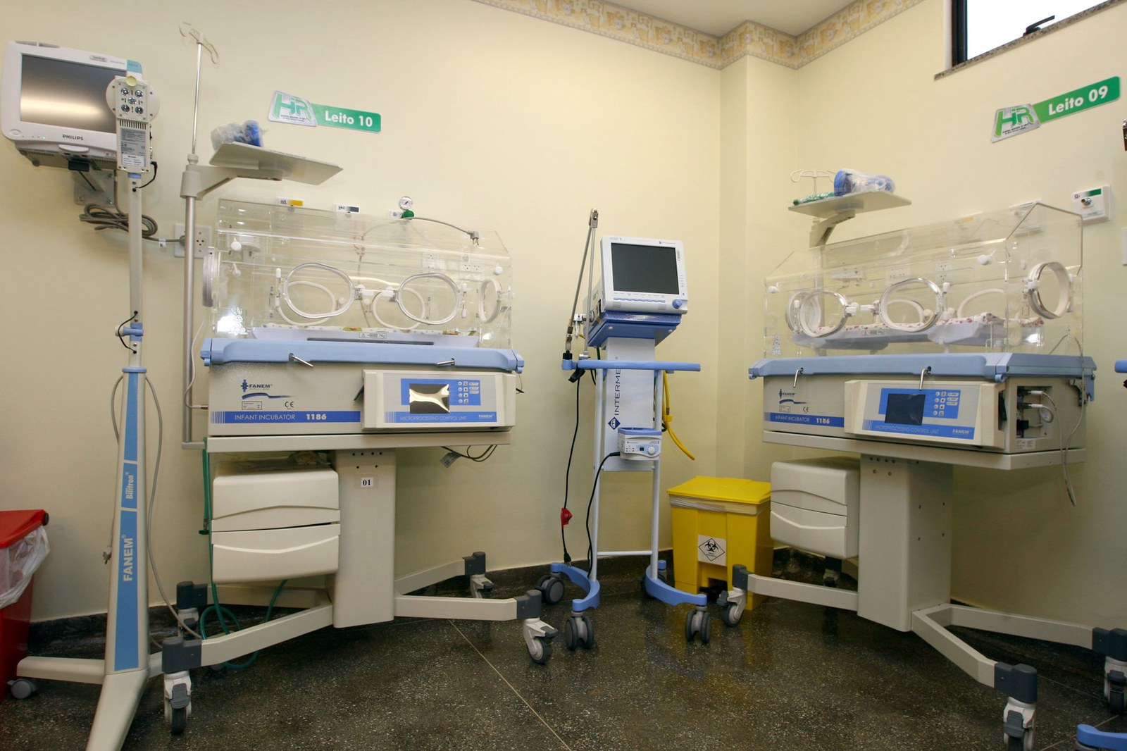 Sala de UTI neonatal com incubadoras, monitores e berços numerados